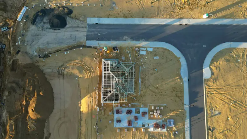 Drone photo of a building frame going up next to a newly paved road